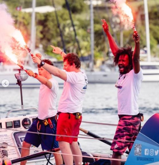 Three graduates stood on a boat each let off small flares