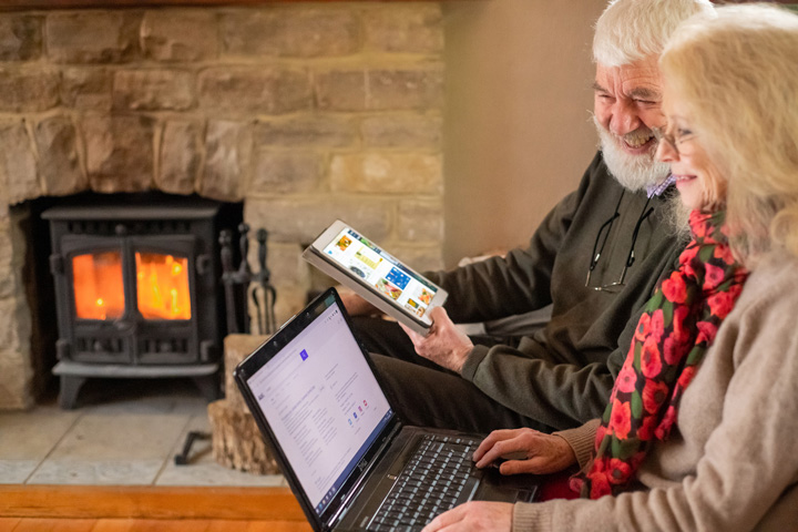 Elderley people using a tablet and a laptop.