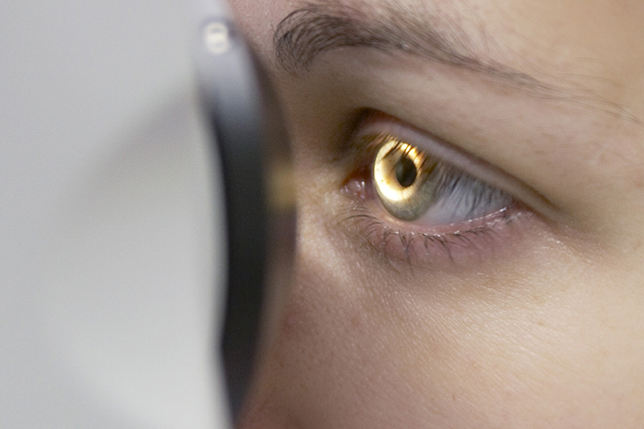 Close up of eye looking through a microscope.