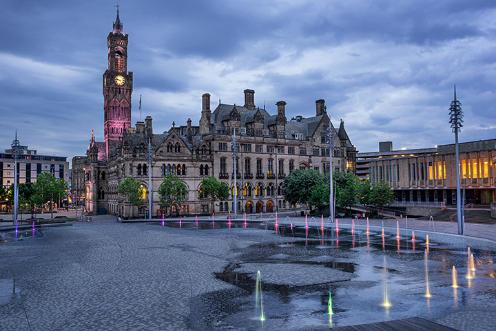 The City Park mirror pool lit up in different colours at dusk