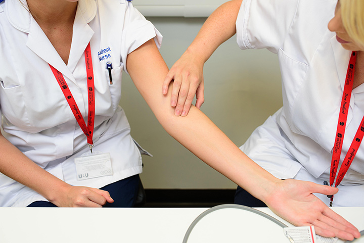 Two student nurses practicing each others blood pressure