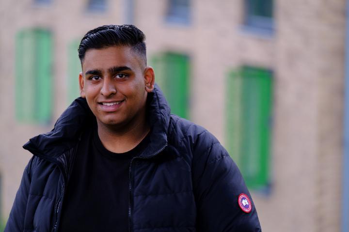 Headshot of Zubayr with a blurred building in the background.