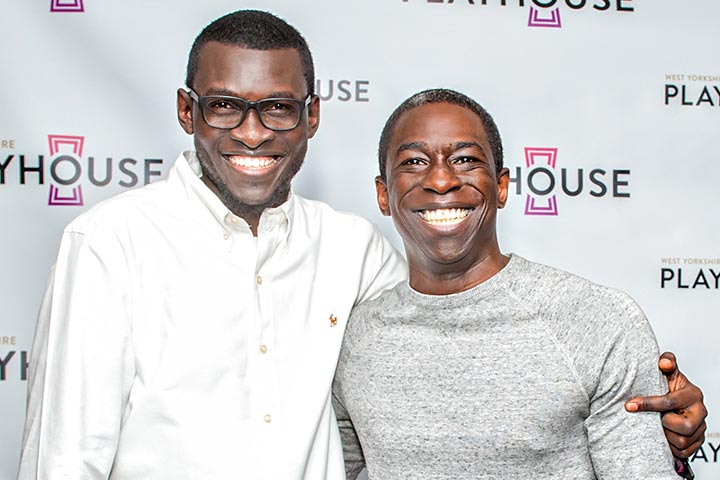 Two smiling people stood in front of a white background.