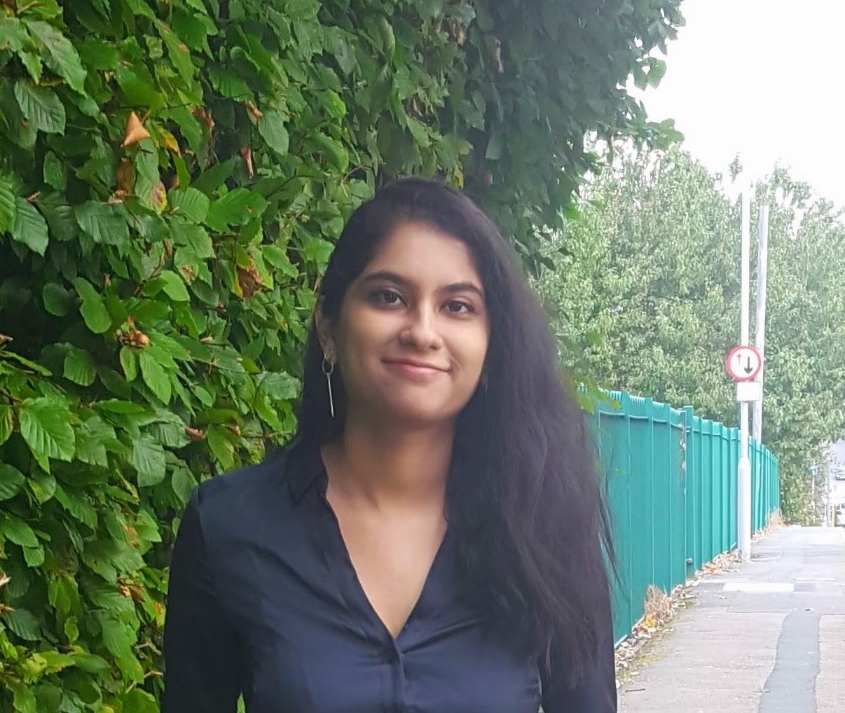 Headshot of Sneha stood next to a bush.