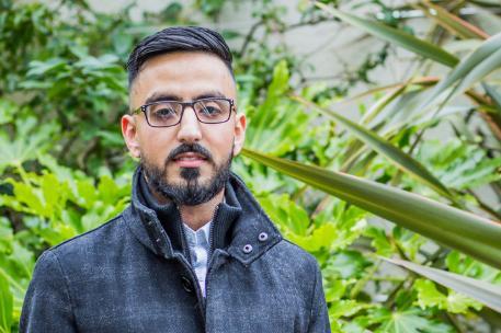 Close up profile image of Master's graduate Mohammed Abaid in front of some green bushes