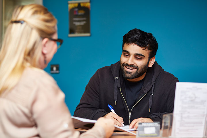 A support advisor helping a student fill in a form