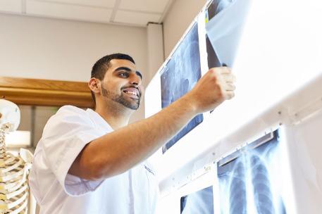 A male student holding up an x-ray image for analysis