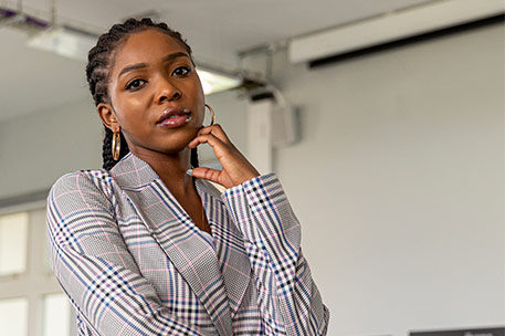 A student stood in a computer room. The student is looking at the camera.