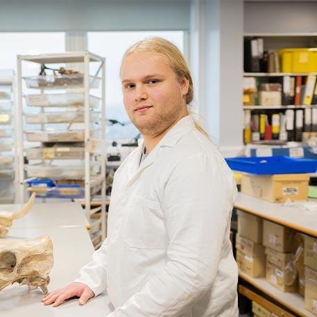 A student smiling at the camera in a lab.