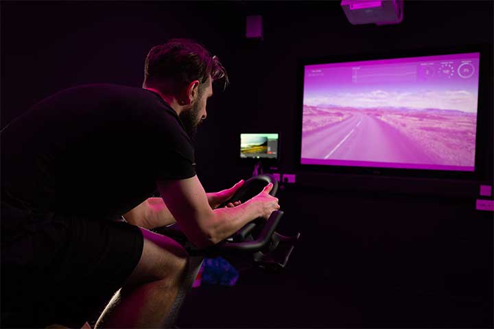 Man on spin bike watching virtual class