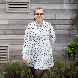 A person standing in front of a grey building.