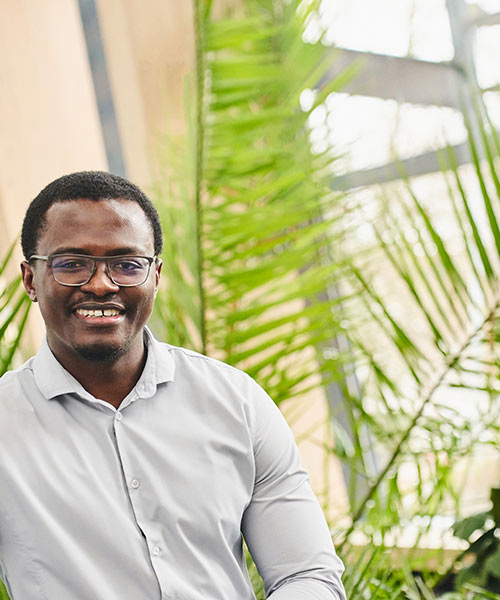 Smiling Student stood in front of plants