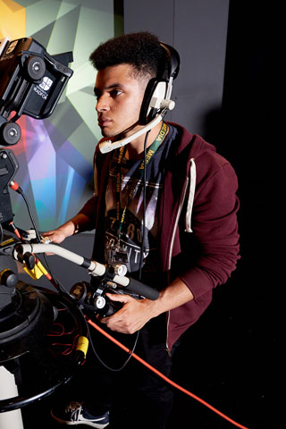 Student looking at monitor behing TV studio camera