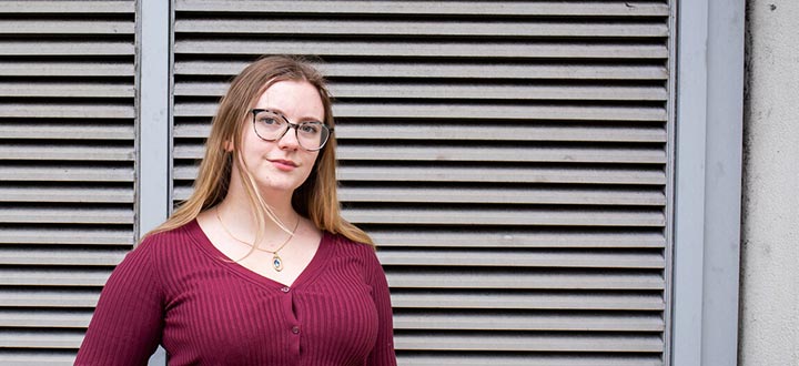 A student wearing a purple cardigan smiles at the camera